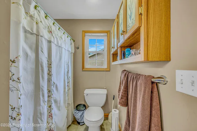 a bathroom with a toilet and a shower curtain