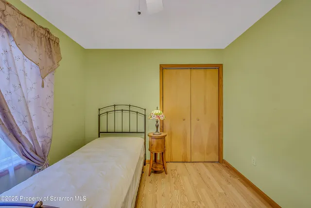 a view of a hallway with wooden floor and a bathroom