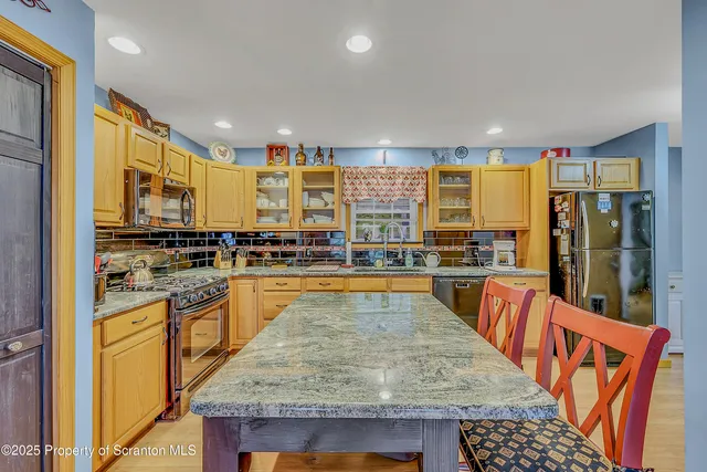 a kitchen with stainless steel appliances granite countertop wooden floor a stove top oven a sink and dishwasher