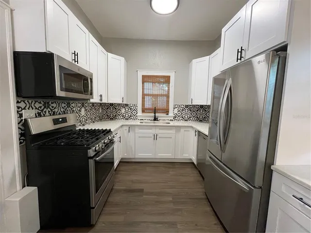 a white kitchen with stainless steel appliances and white cabinets