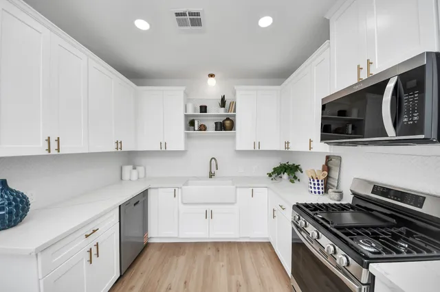 a kitchen with cabinets stainless steel appliances and a potted plant