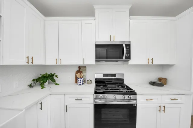a kitchen with stainless steel appliances a white stove top oven a sink dishwasher and a microwave with wooden floor