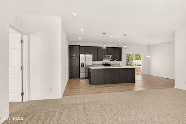 a view of kitchen with a sink wooden cabinets and window
