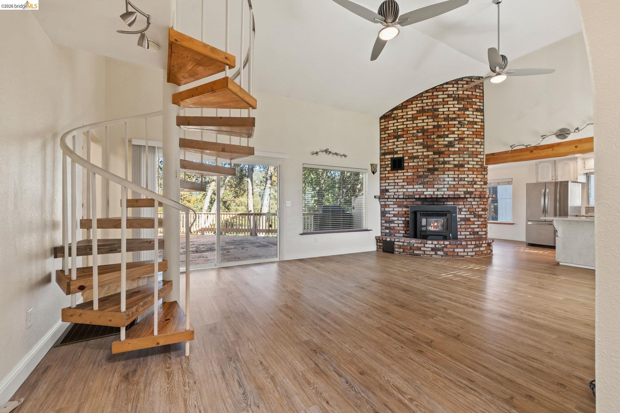 21916 Phoenix Lake Road Sonora, CA 95370 - Photo 7 of 48 an empty room with wooden floor fireplace and windows