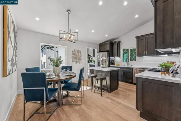 a kitchen with a dining table chairs wooden floor and appliances