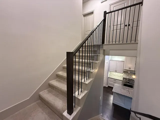 a view of staircase with railing and white walls