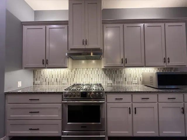 a kitchen with granite countertop white cabinets and stainless steel appliances