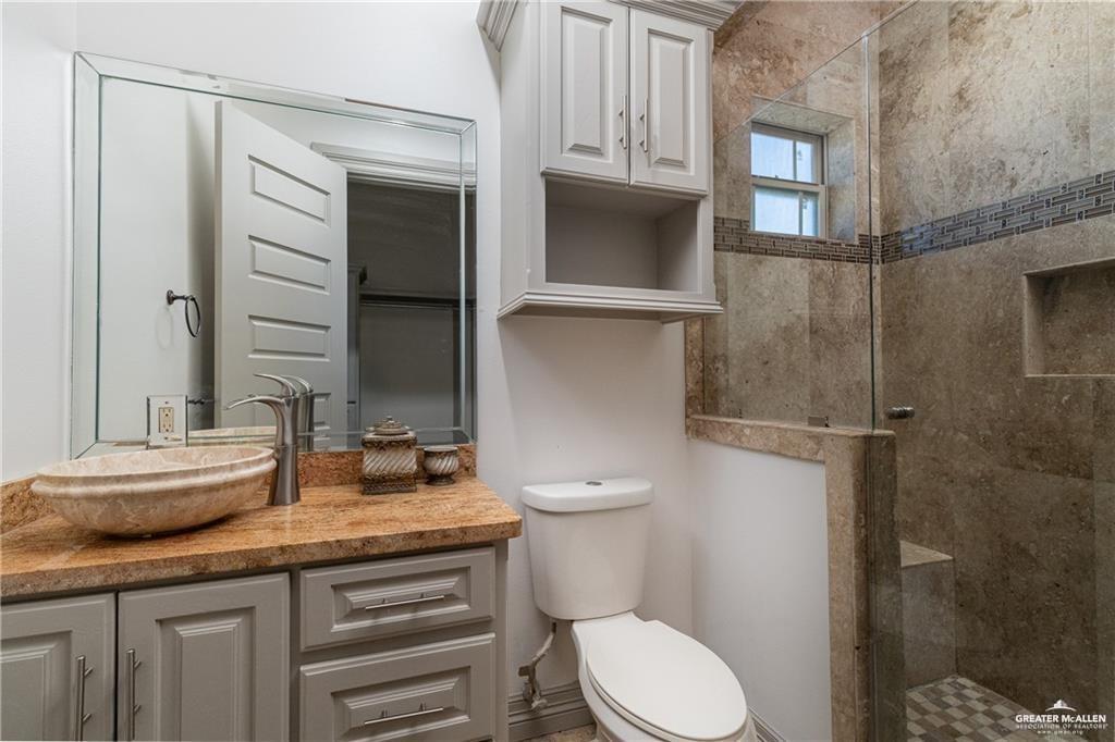 1205 Travis Street Mission, TX 78572 - Photo 26 of 45 a bathroom with a granite countertop sink toilet and shower