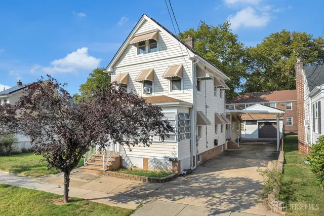 a white house that has tree in front of it