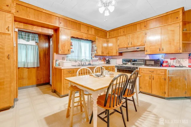 a kitchen with stainless steel appliances kitchen island granite countertop a dining table chairs and a refrigerator
