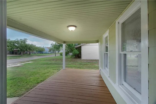 a view of a porch with wooden floor and a yard
