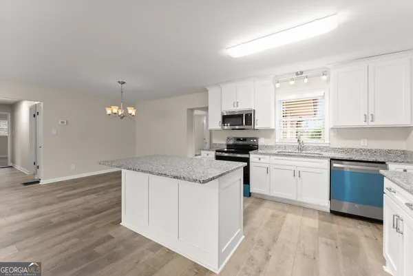 a kitchen with granite countertop white cabinets and white appliances