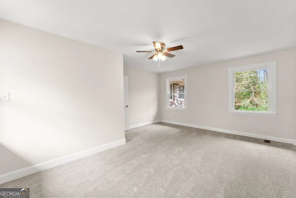 an empty room with windows and chandelier fan