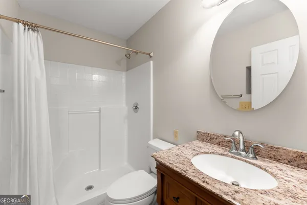 a bathroom with a granite countertop sink toilet a mirror and shower