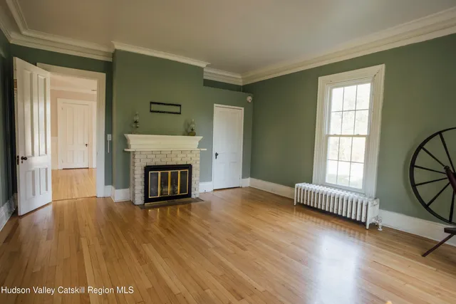 an empty room with wooden floor fireplace and windows
