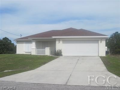 1541 Meadow Road Lehigh Acres, FL 33976 - Photo 1 of 3 a front view of a house with a yard and garage