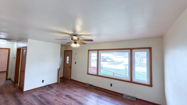 an empty room with windows and fan