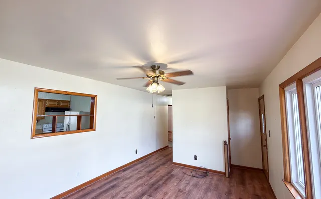 a view of an empty room with window and wooden floor