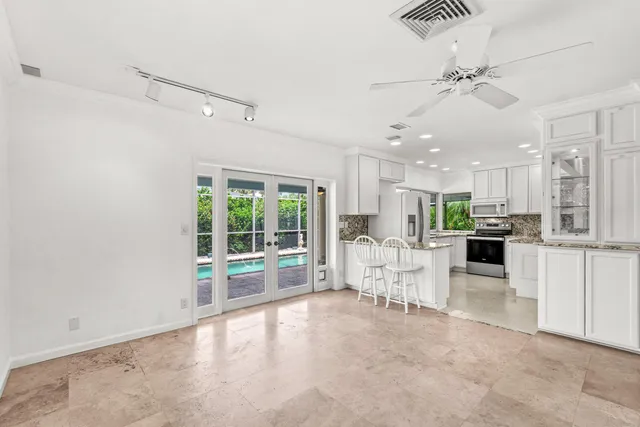 a large white kitchen with a large window appliances and cabinets