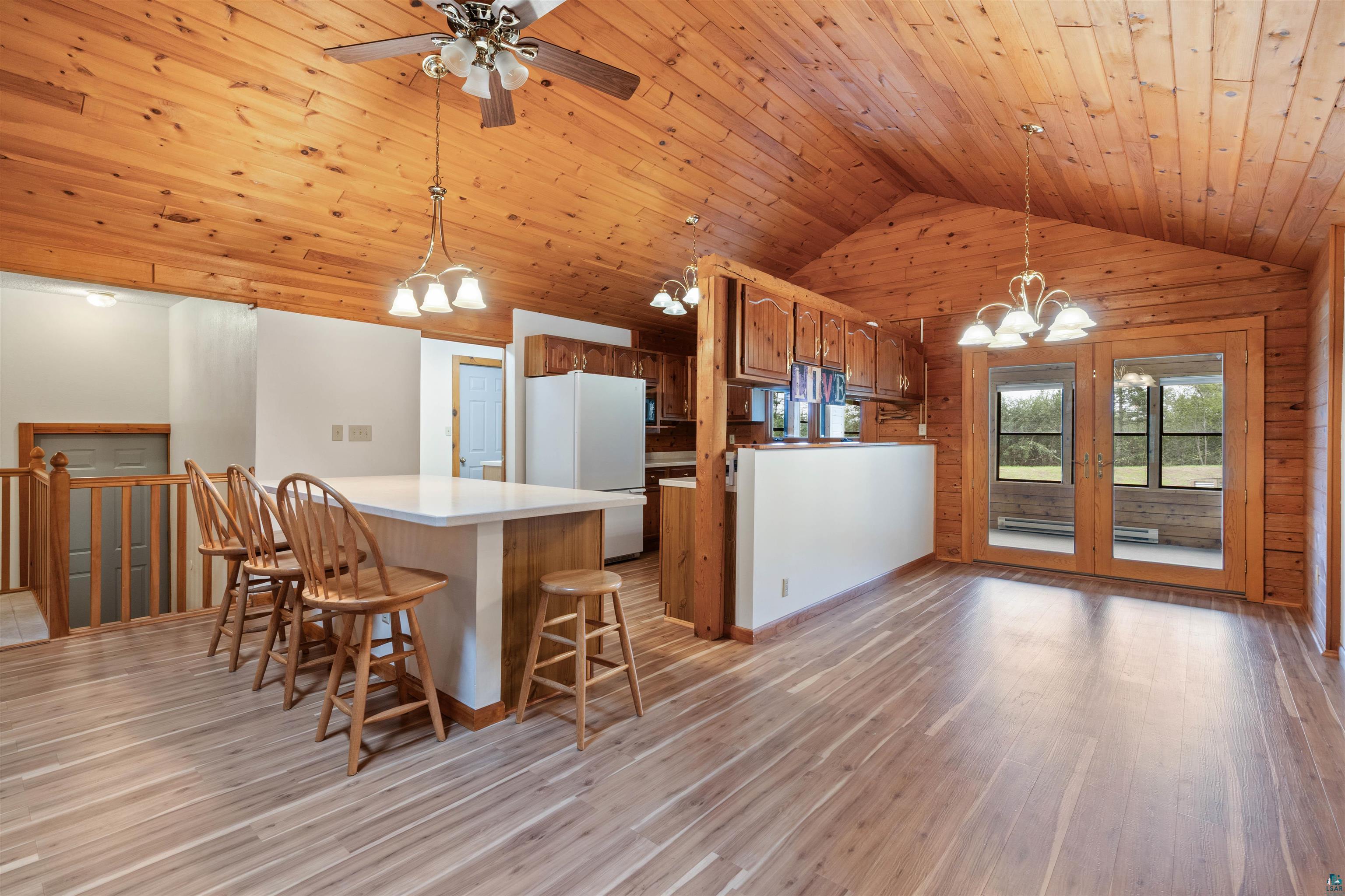 5373 Lester River Road Duluth, MN 55804 - Photo 5 of 39 Vaulted wood-paneled ceiling with exposed beams, wood-finish flooring, kitchen island with counter seating, wood cabinetry, and double glass doors