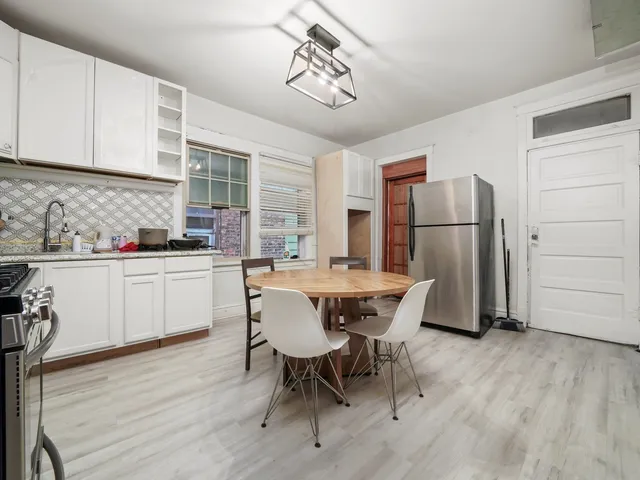 a kitchen with stainless steel appliances a dining table chairs refrigerator and cabinets