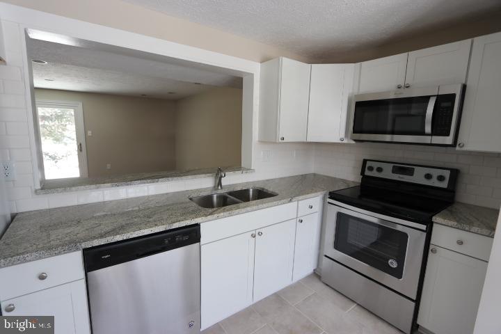 10149 Shelldrake Circle Damascus, MD 20872 - Photo 14 of 28 a kitchen with granite countertop a sink dishwasher stove and microwave with wooden cabinets
