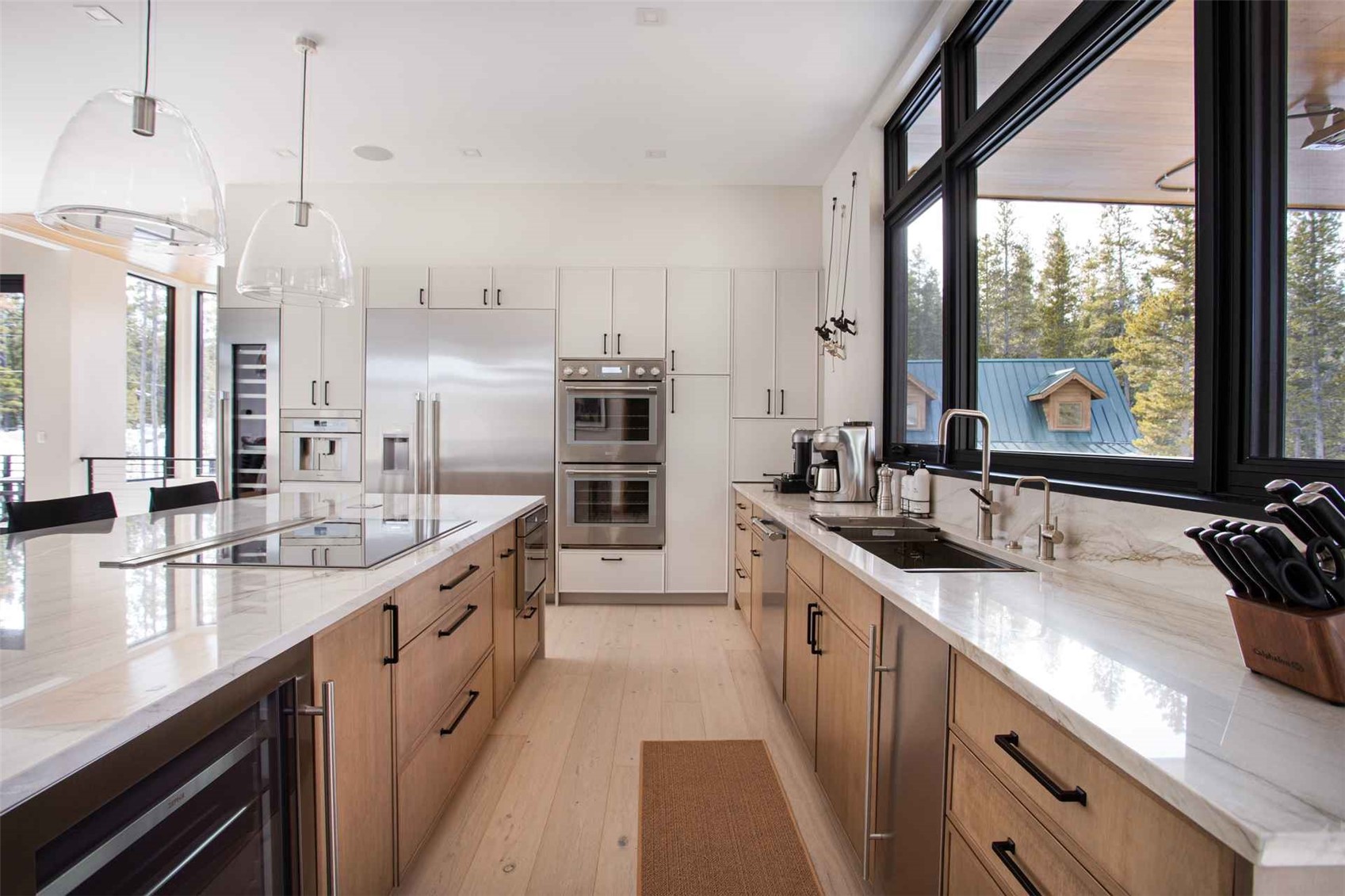 3764 Ski Hill Road Breckenridge, CO 80424 - Photo 6 of 30 Two tone kitchen featuring light stone counters, stainless steel appliances, pendant lighting, dual tone cabinetry, and beverage cooler