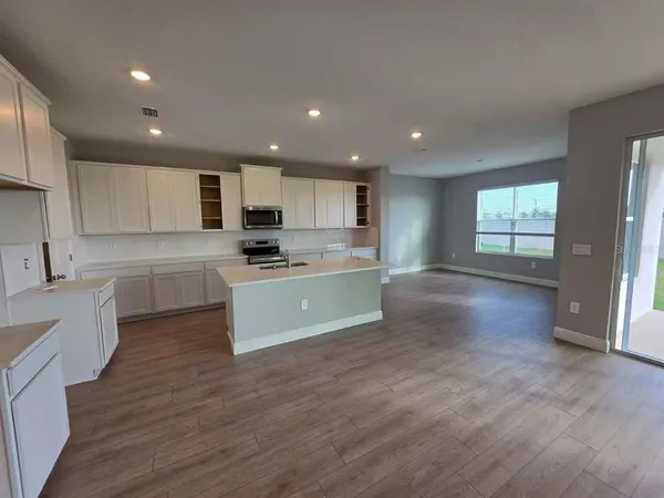 a large kitchen with kitchen island a sink dishwasher a stove and a refrigerator with wooden floor
