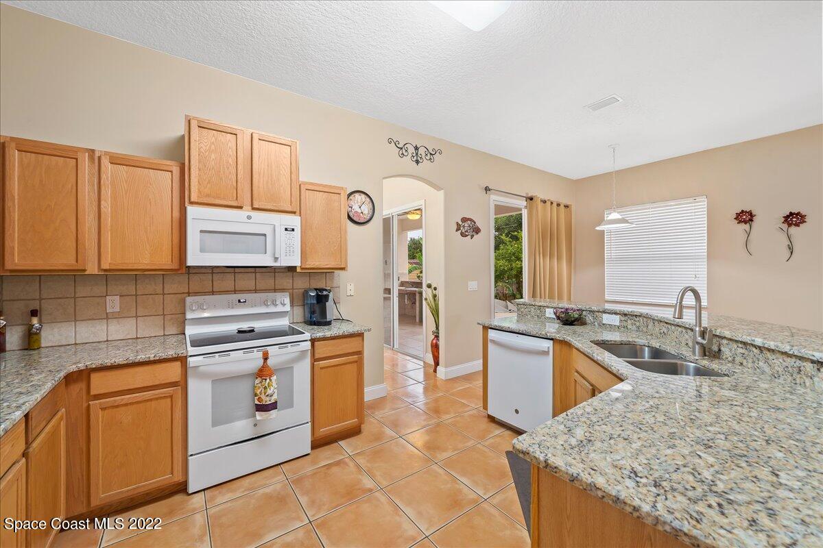 6949 Bryant Road Cocoa, FL 32927 - Photo 12 of 33 a kitchen with stainless steel appliances granite countertop a sink stove and refrigerator