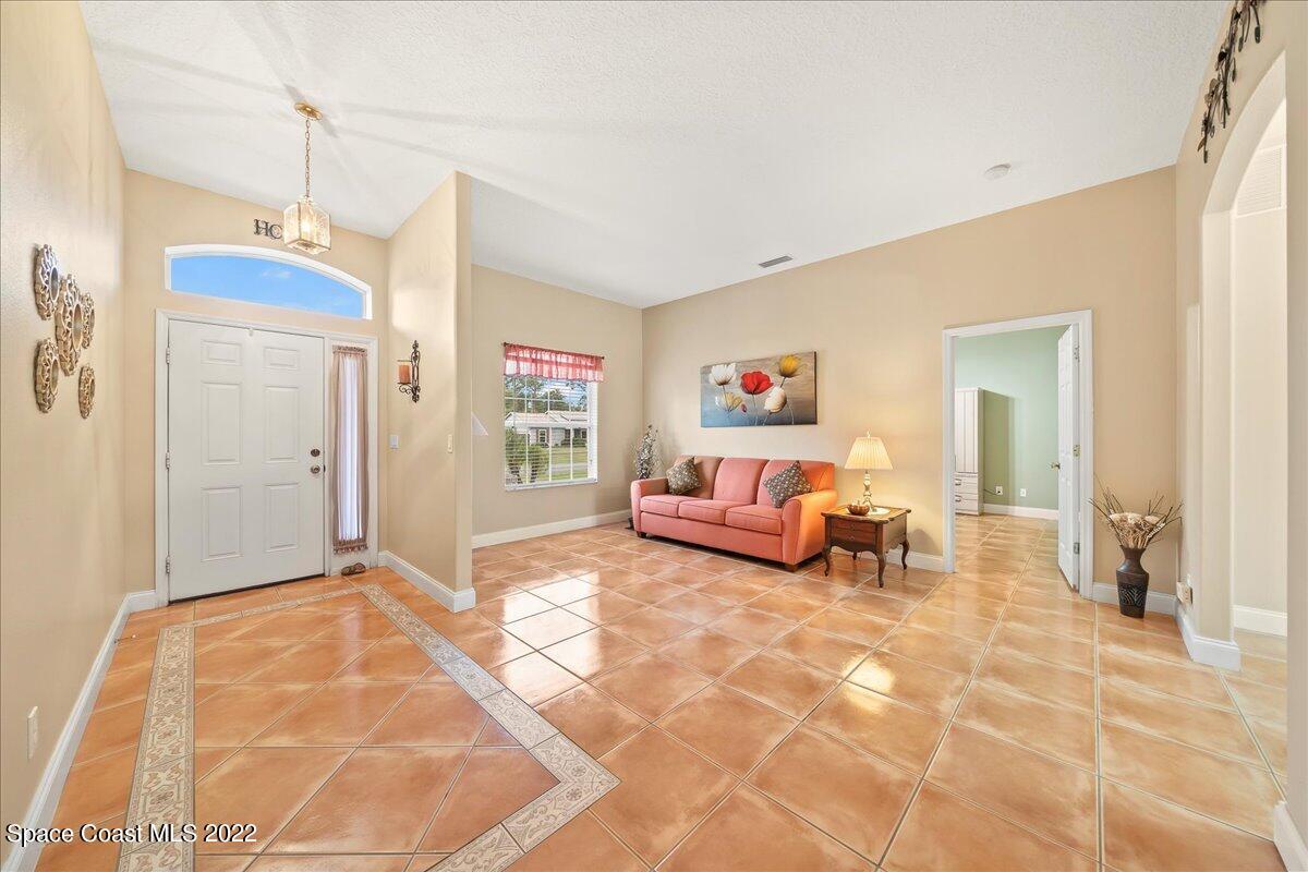 6949 Bryant Road Cocoa, FL 32927 - Photo 3 of 33 a spacious bedroom with a bed and a chandelier