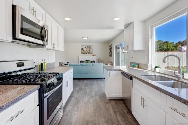 a kitchen with stainless steel appliances a sink a stove top oven a refrigerator cabinets and wooden floor