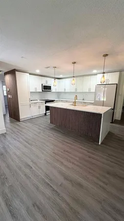 an empty room with wooden floor windows and fan