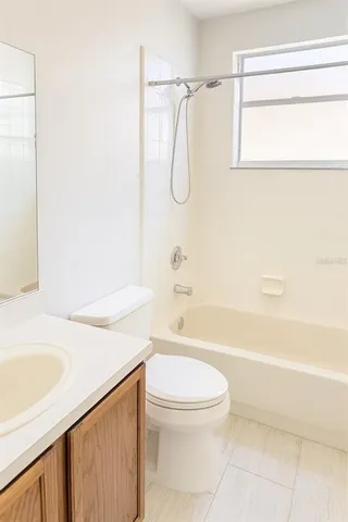 a bathroom with a granite countertop bathtub shower sink vanity and toilet