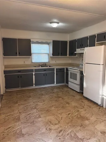 a kitchen with granite countertop a refrigerator and a stove top oven