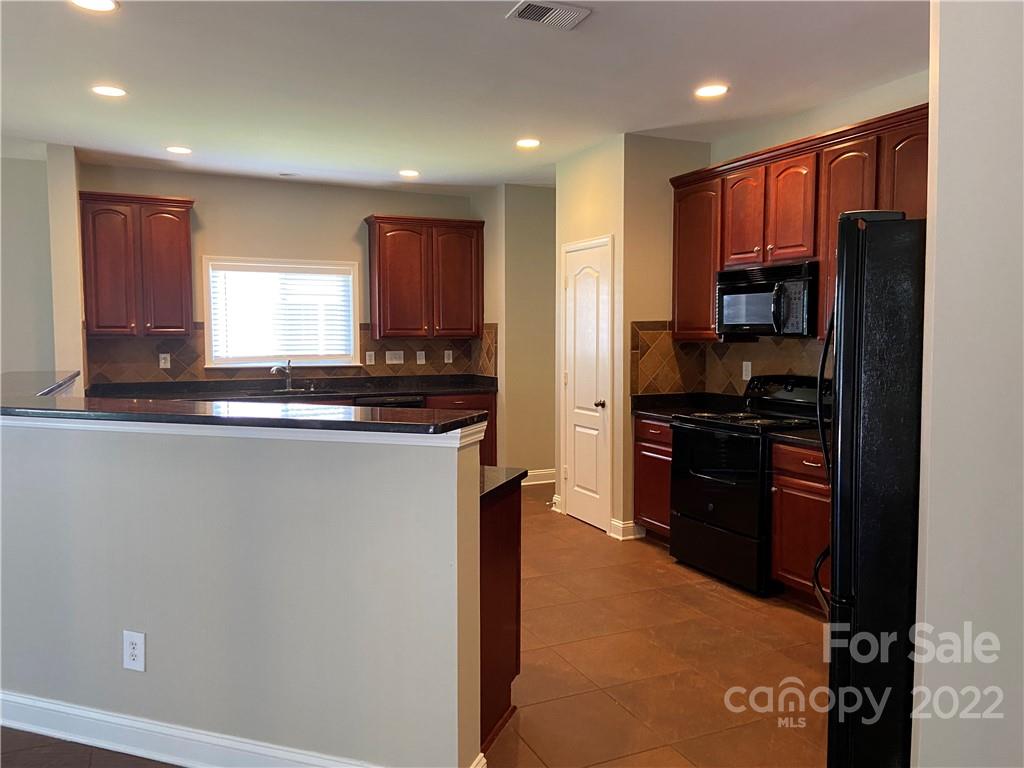 6734 Evanton Loch Road Charlotte, NC 28278 - Photo 16 of 34 a kitchen with granite countertop a refrigerator and a stove top oven