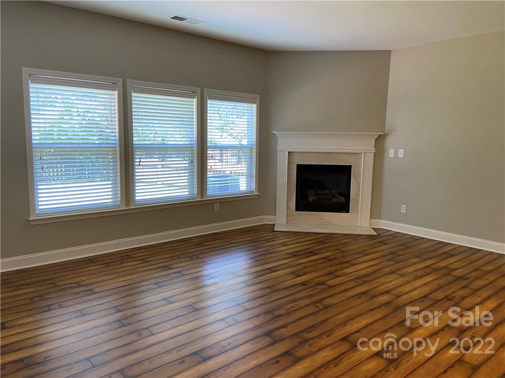 6734 Evanton Loch Road Charlotte, NC 28278 - Photo 19 of 34 a view of an empty room with wooden floor windows and a fireplace