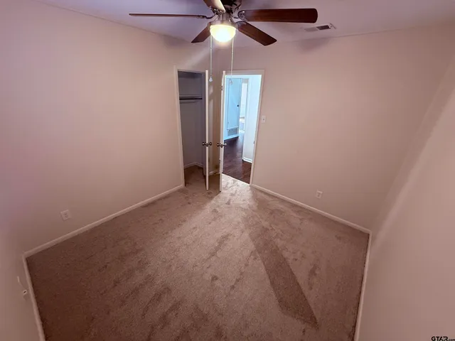 an empty room with closet and a chandelier fan