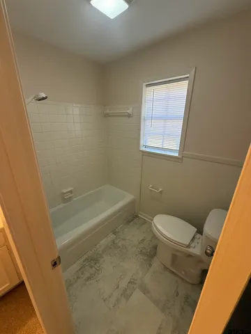 a bathroom with a granite countertop toilet a sink and a bathtub