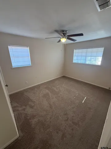 an empty room with a ceiling fan and a window