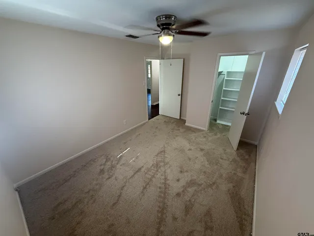 en empty room with windows and fan