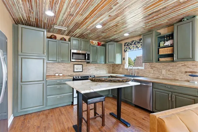 a kitchen with stainless steel appliances granite countertop a sink stove refrigerator and cabinets