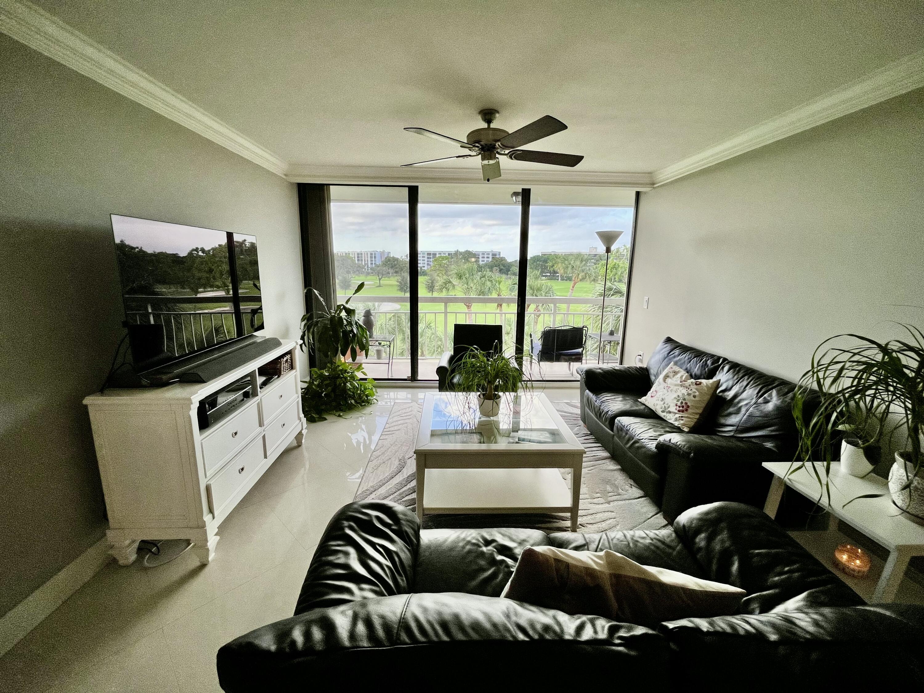 6169 Balboa Circle, Unit 401 Boca Raton, FL 33433 - Photo 14 of 34 a living room with furniture a flat screen tv and a floor to ceiling window