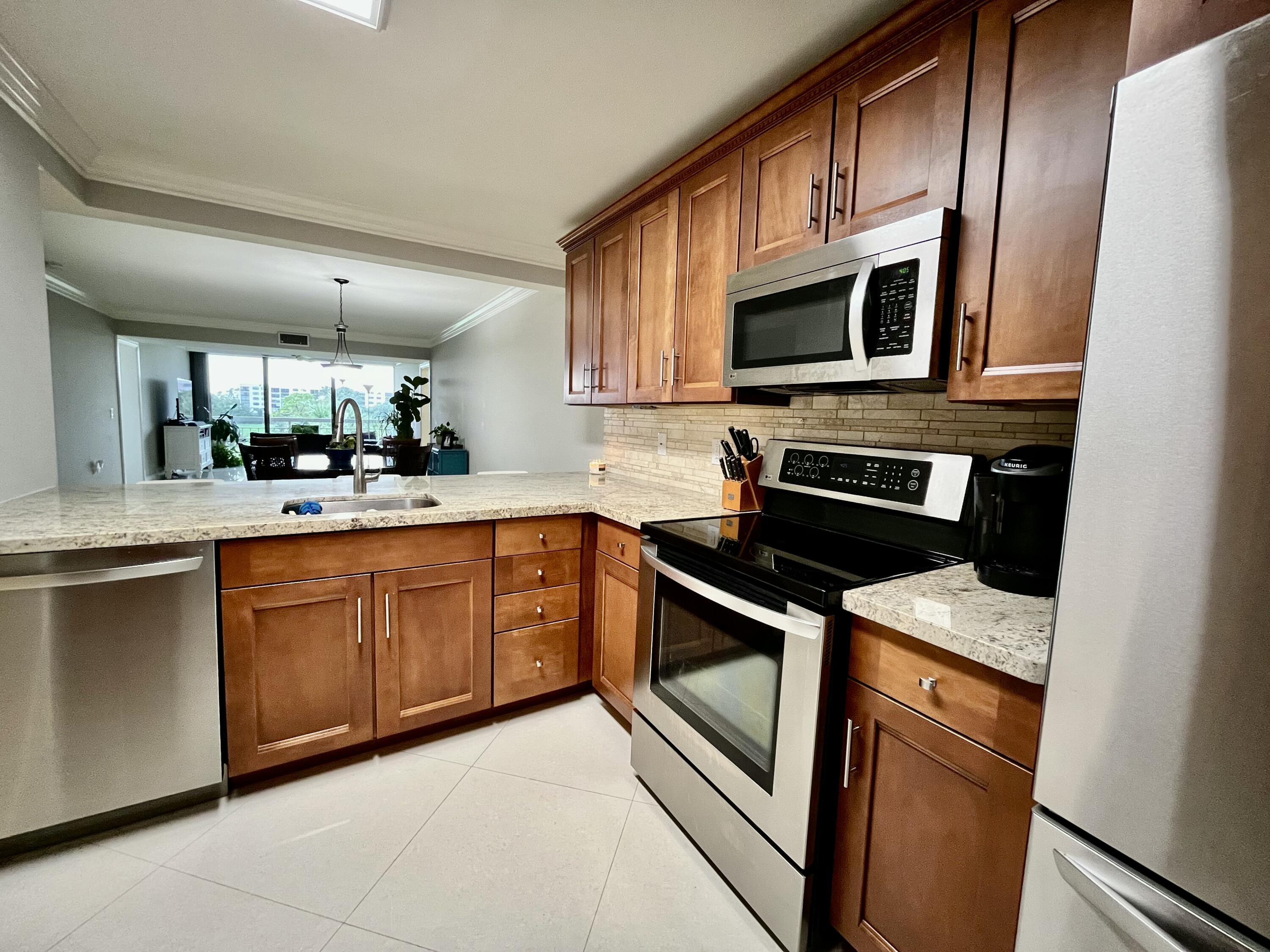 6169 Balboa Circle, Unit 401 Boca Raton, FL 33433 - Photo 9 of 34 a kitchen with stainless steel appliances granite countertop a stove microwave and sink