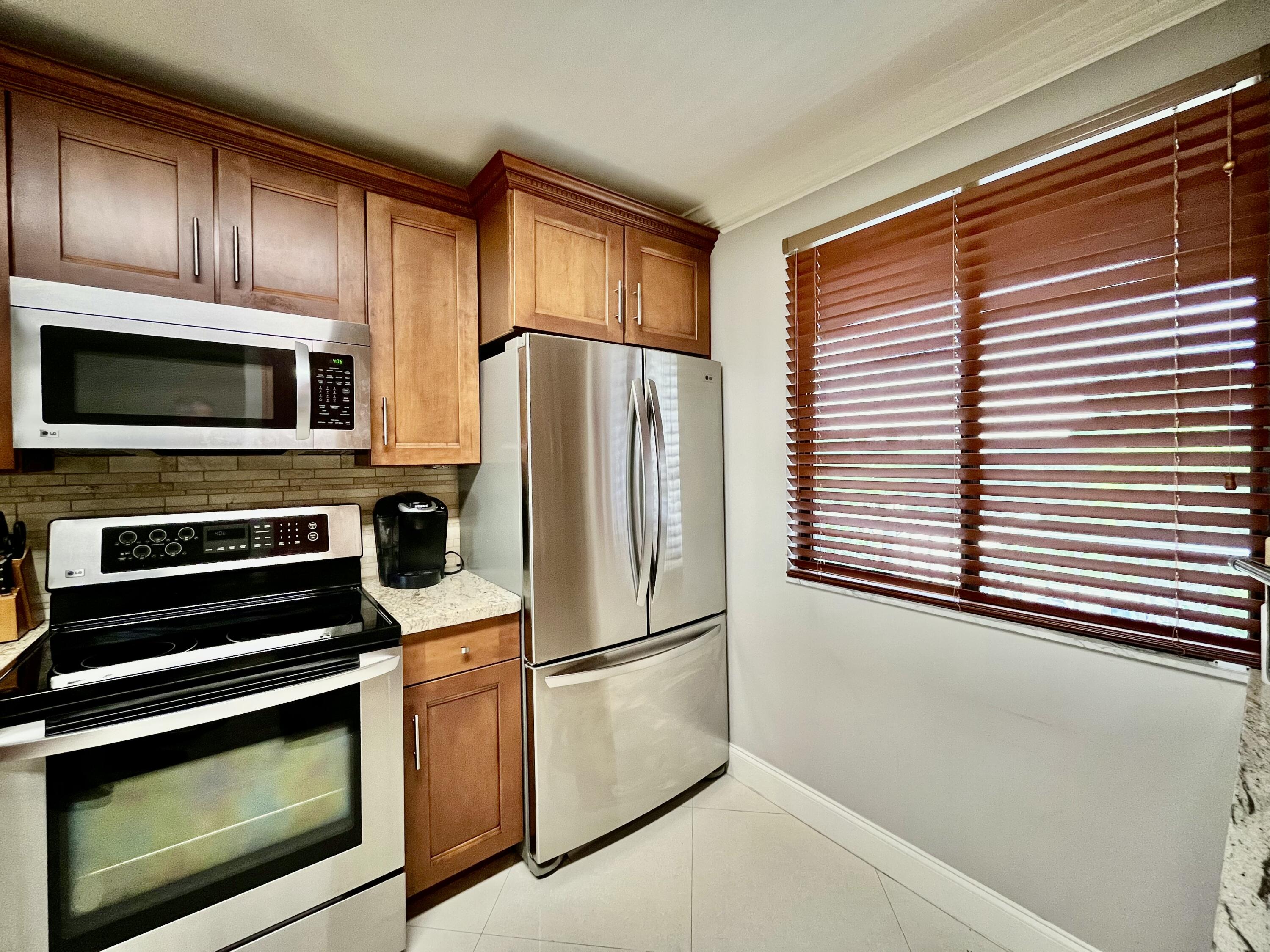 6169 Balboa Circle, Unit 401 Boca Raton, FL 33433 - Photo 10 of 34 a kitchen with granite countertop a refrigerator and a stove top oven