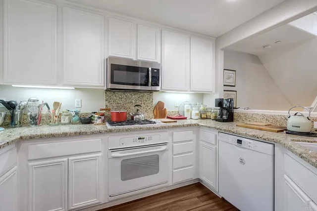 a kitchen with granite countertop white cabinets sink and stainless steel appliances