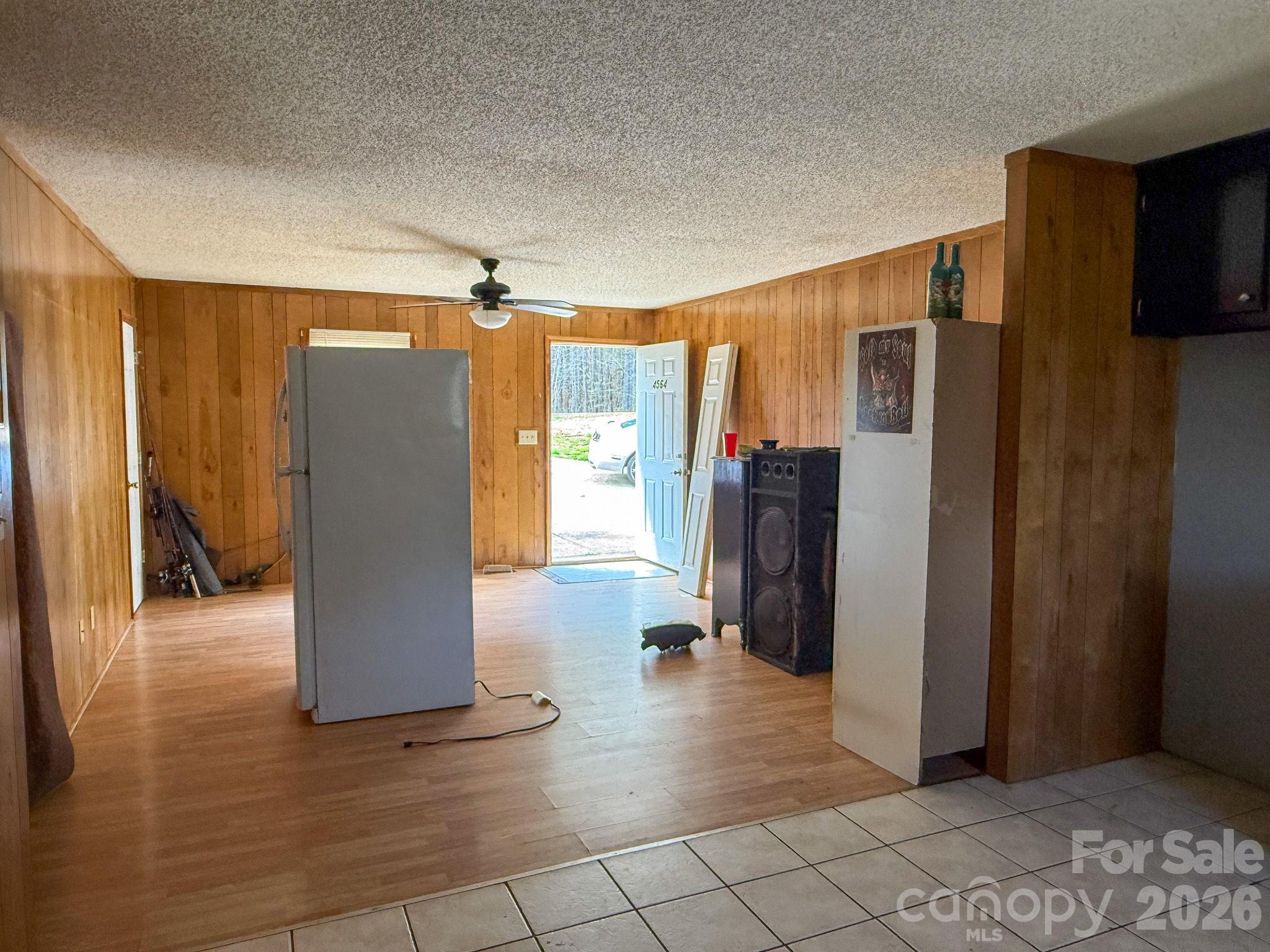 4562 Grassy Creek Road Denver, NC 28037 - Photo 12 of 24 a view of a refrigerator in kitchen and an empty room and wooden shelves