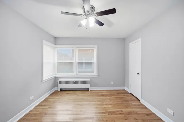an empty room with wooden floor fan and windows