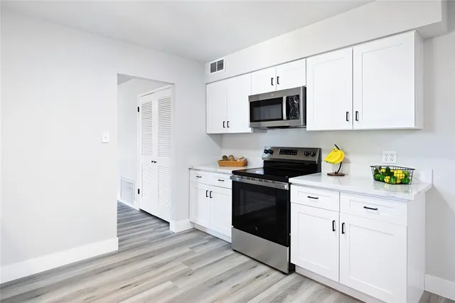 a kitchen with stainless steel appliances white cabinets and a stove top oven
