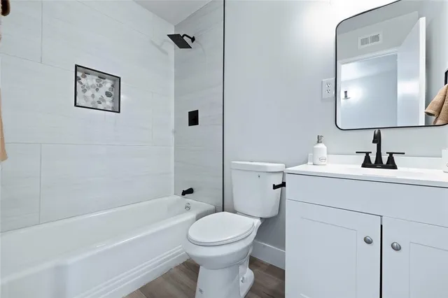 a bathroom with a toilet sink vanity tub and mirror