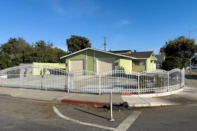 a view of a house with a small yard and wooden fence